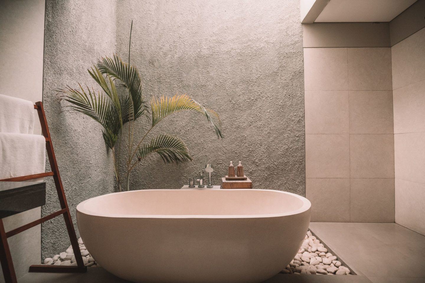 a free standing tub next to an indoor palm tree