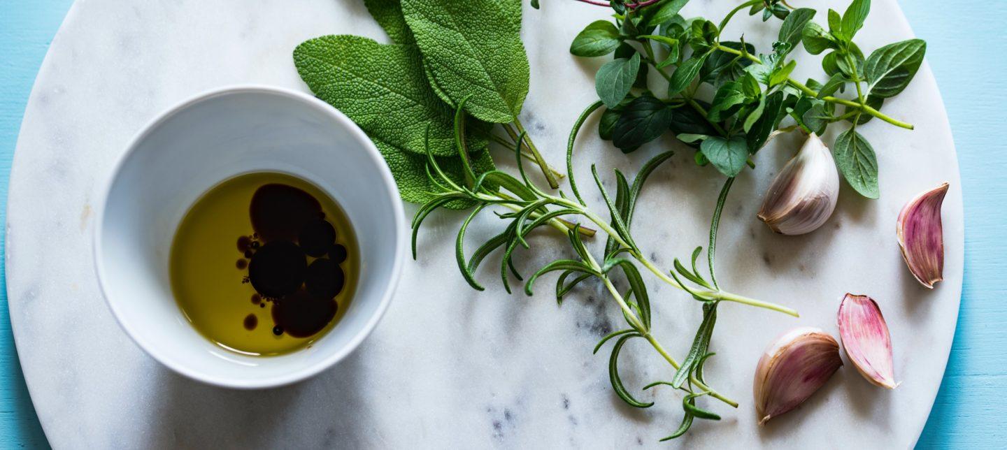 Olive oil on a table surronded by herbs