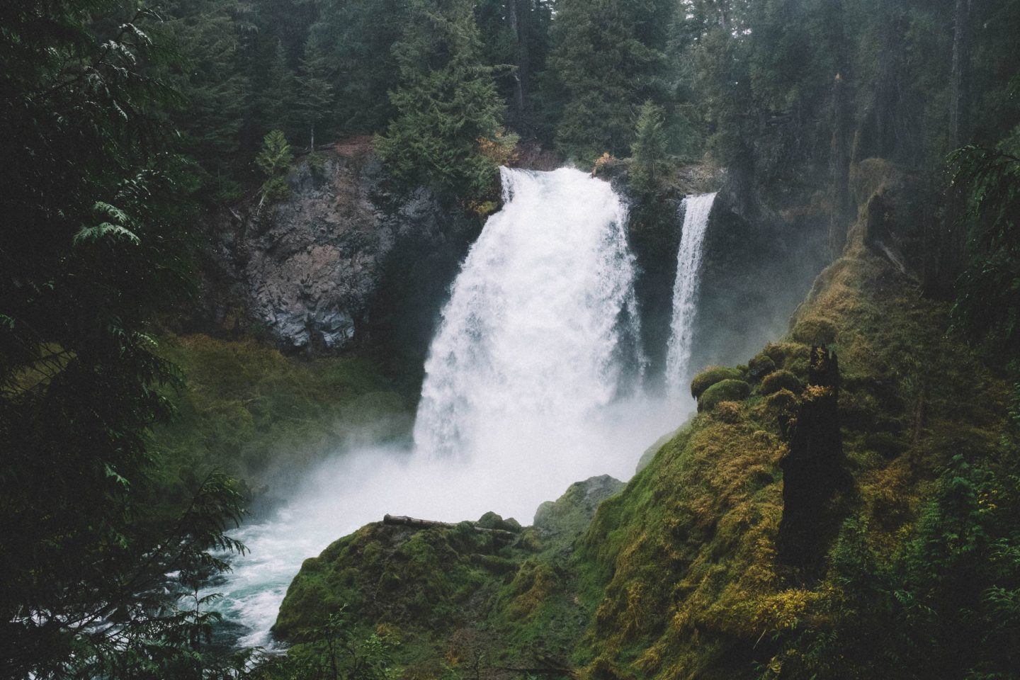 Cascata d'acqua, che si schianta contro delle rocce verdi e muschiose