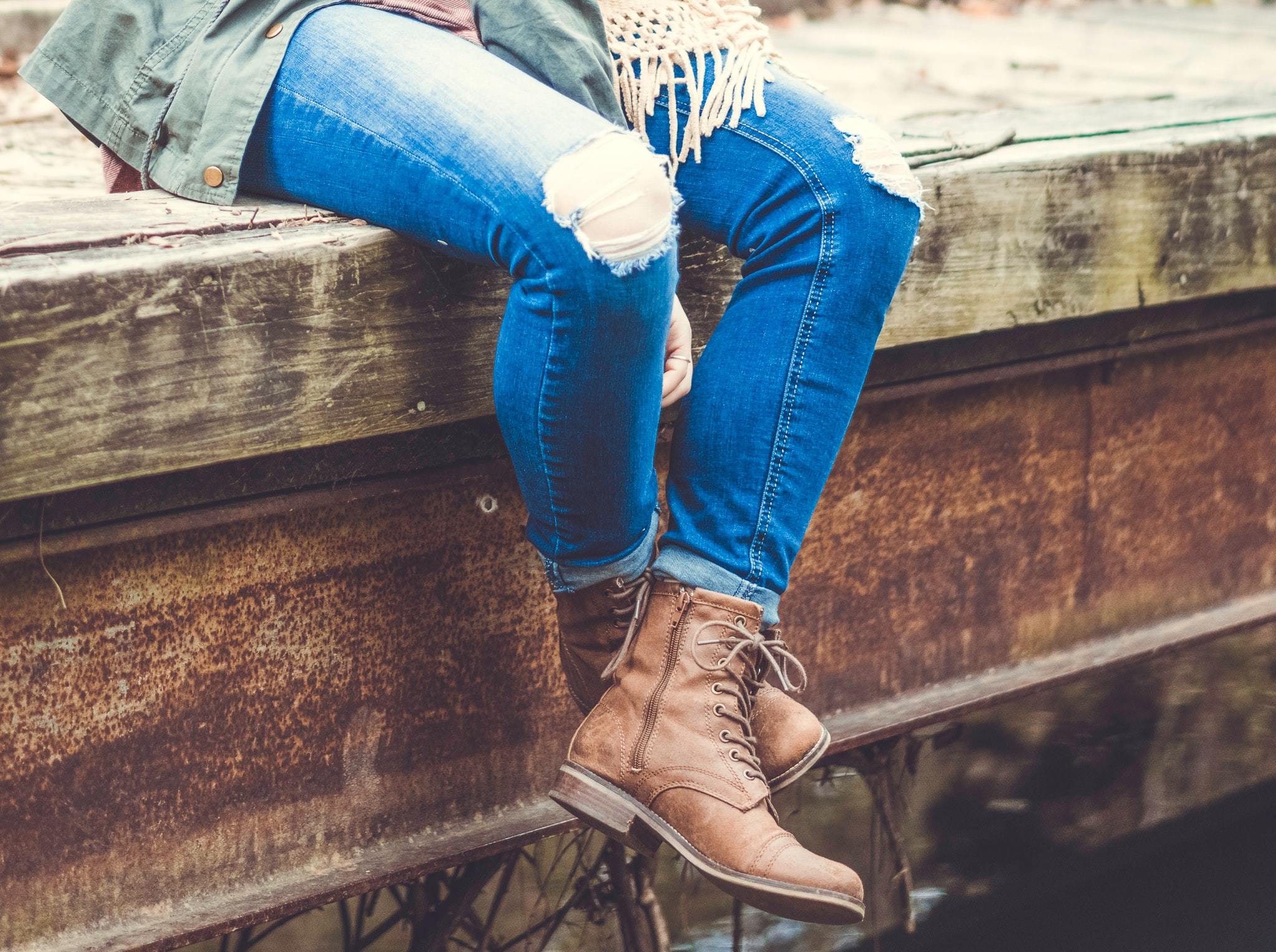 Pregnant person, sitting on a dock with their legs dangling over