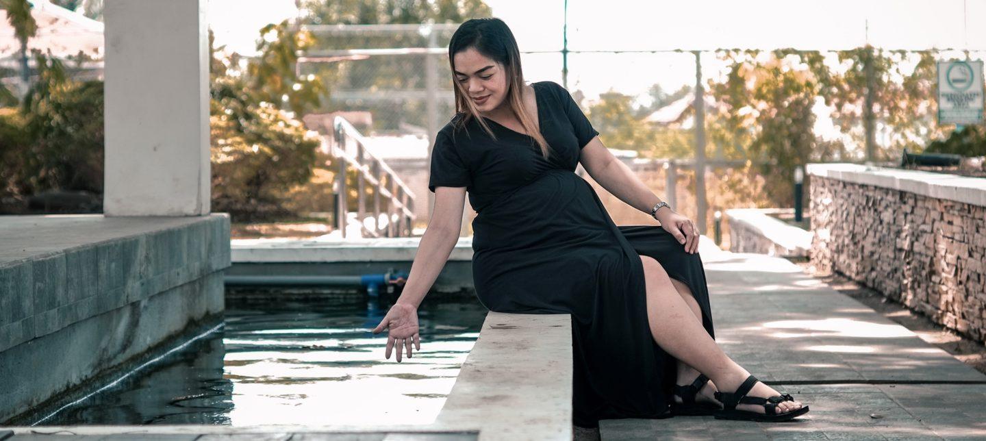 pregnant woman sitting by water fountain