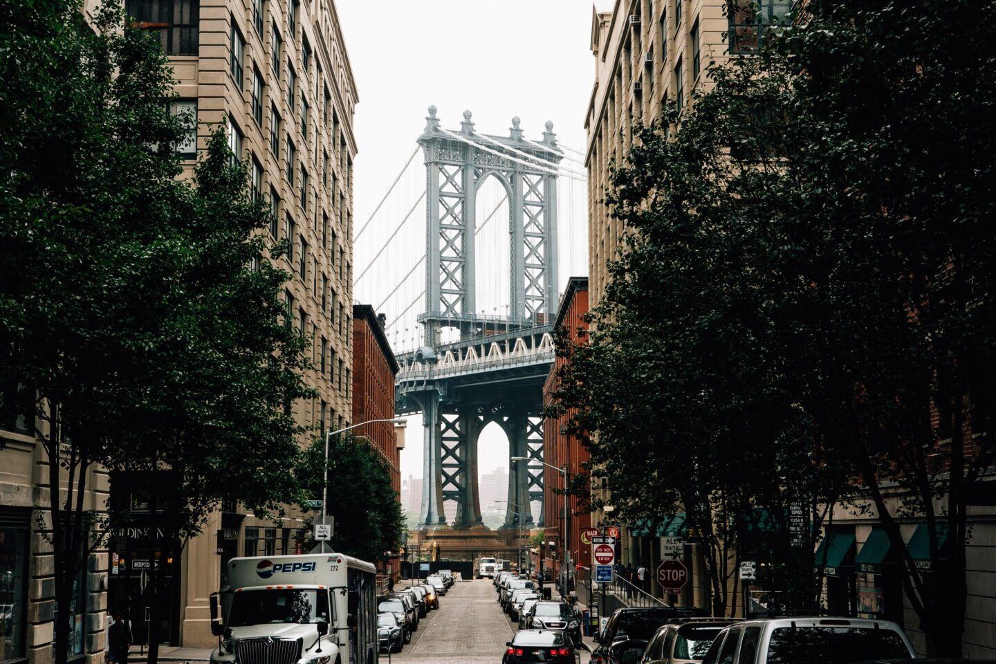Classic Brooklyn street, with a cobbled road and brownstone houses, looking at the Brooklyn bridge