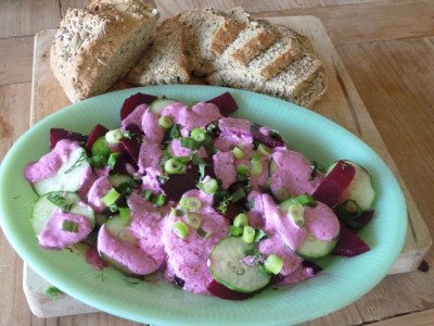 finished beet and cucumber salad with pink dressing on a mint green plate