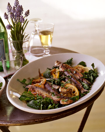 a meal of a protein and greens sitting on a table with fresh flowers