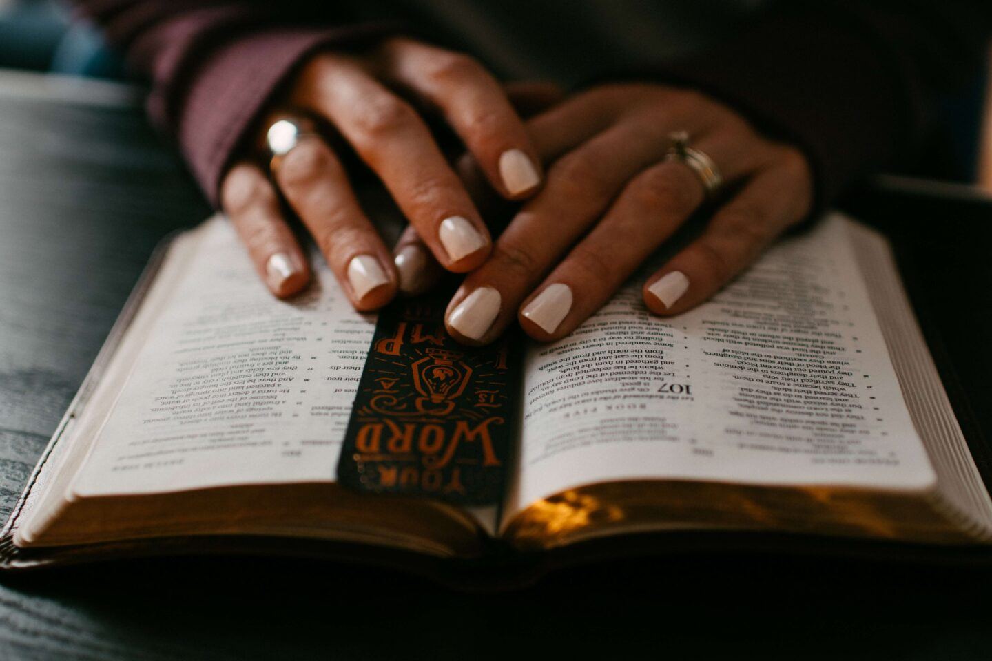 A close up of some hands, gently resting on a book, as the person sitting there is reading