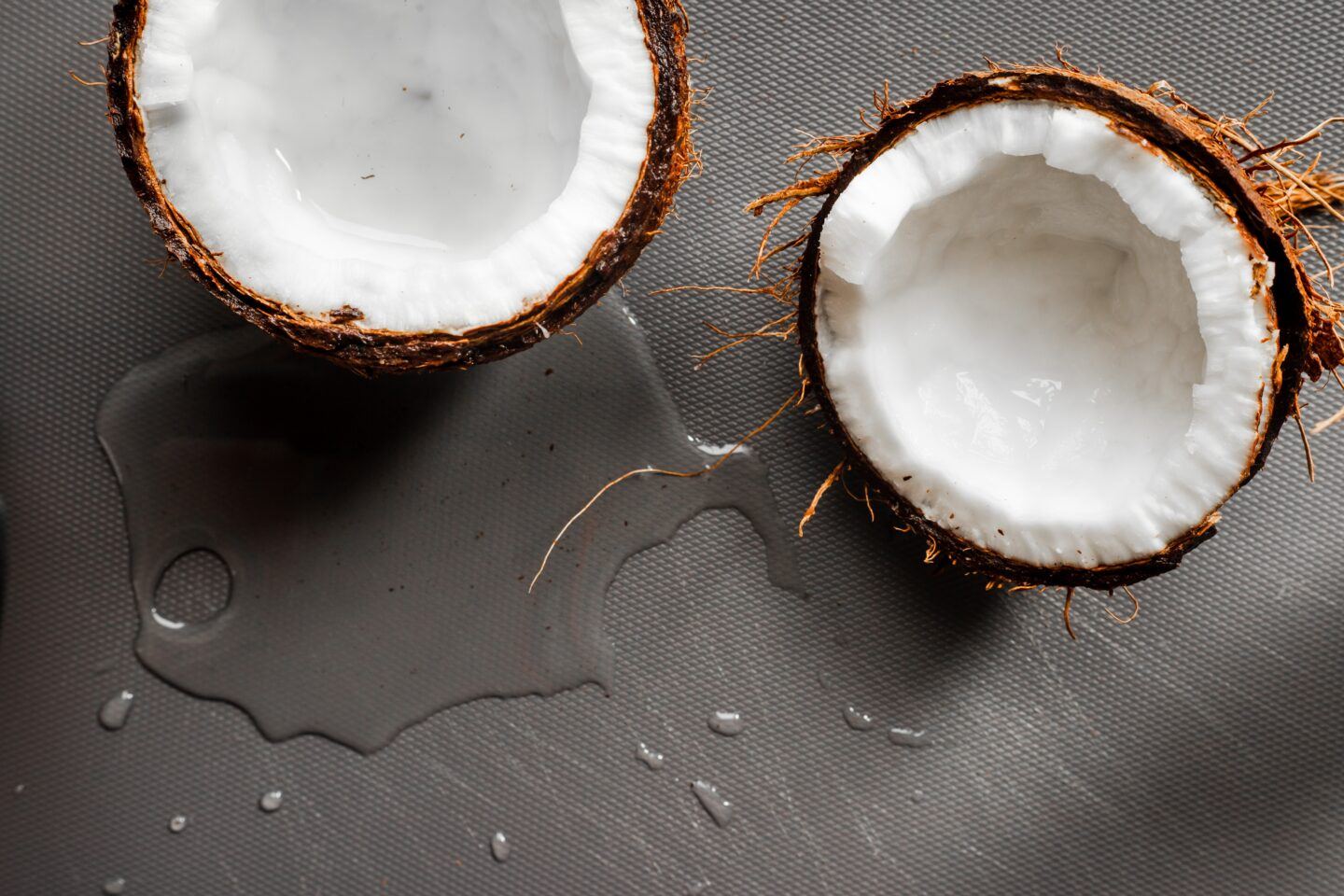 a broken open coconut with water next to it
