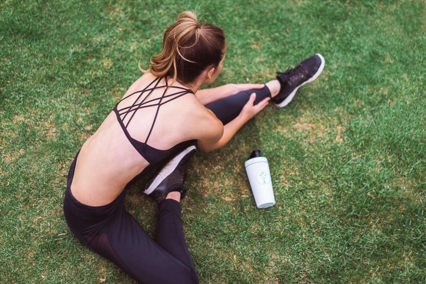 a woman in athletic wear stretching on green grass
