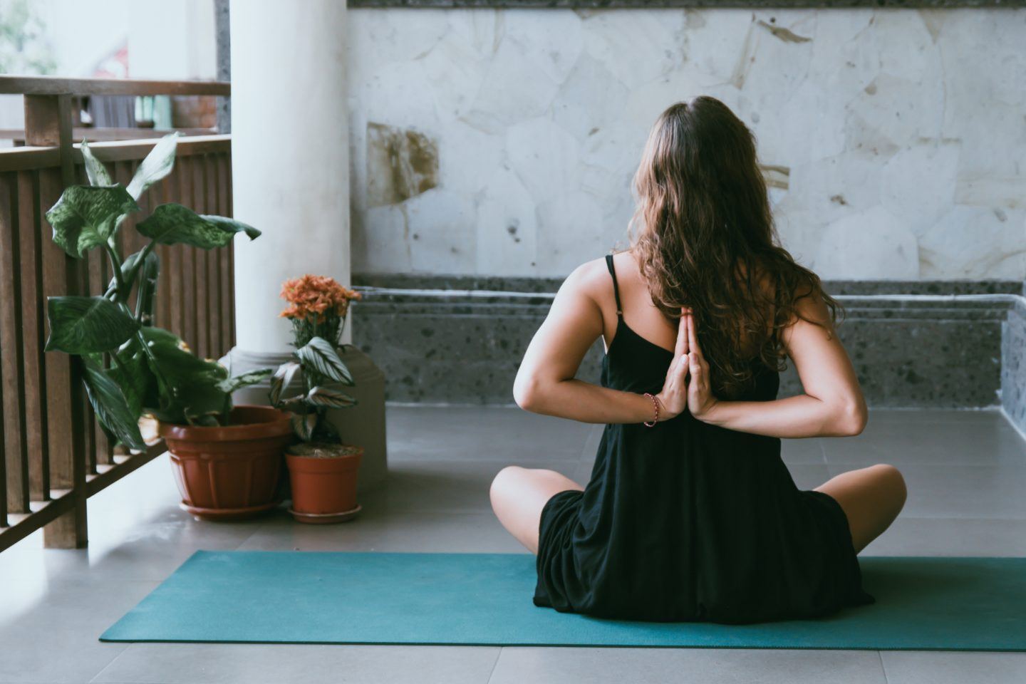 Woman sitting on yoga mat with arms behind her back