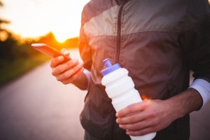 a closeup of someone holding a water bottle and a cell phone