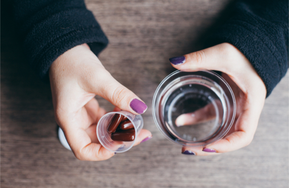 a close up shot of pills and a glass of water 