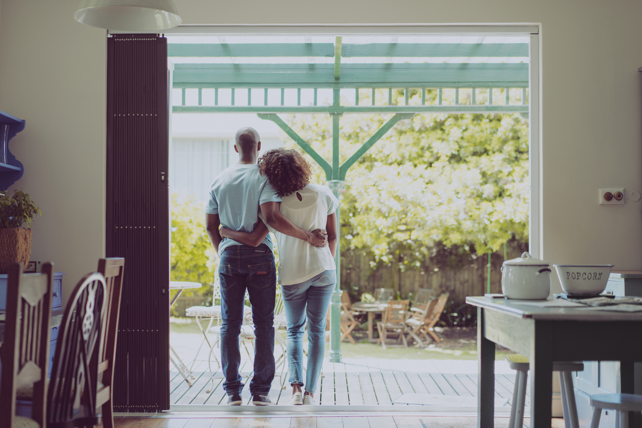 a couple standing in an open doorway with the woman leaning her head on the man's shoulder