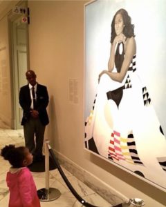 Photographed by Ben Hines, Jessica Curry - Photo of a young black girl looking at a photo of Michelle Obama