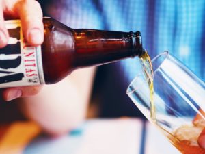 a close up of someone pouring a beer into a glass 