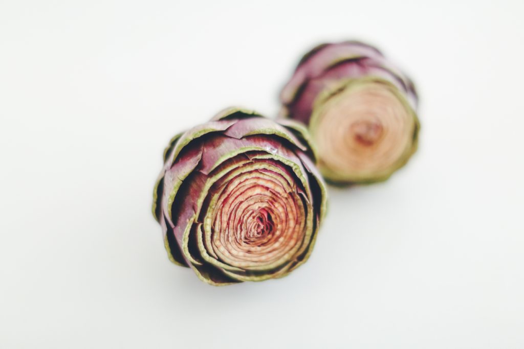 whole artichokes against plain gray background