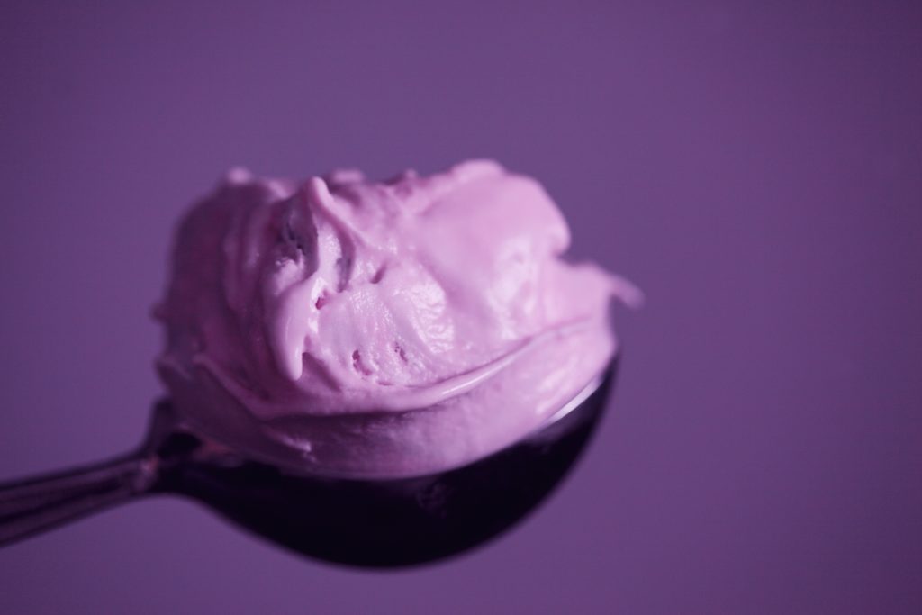 purple sherbet on a spoon in front of a purple background