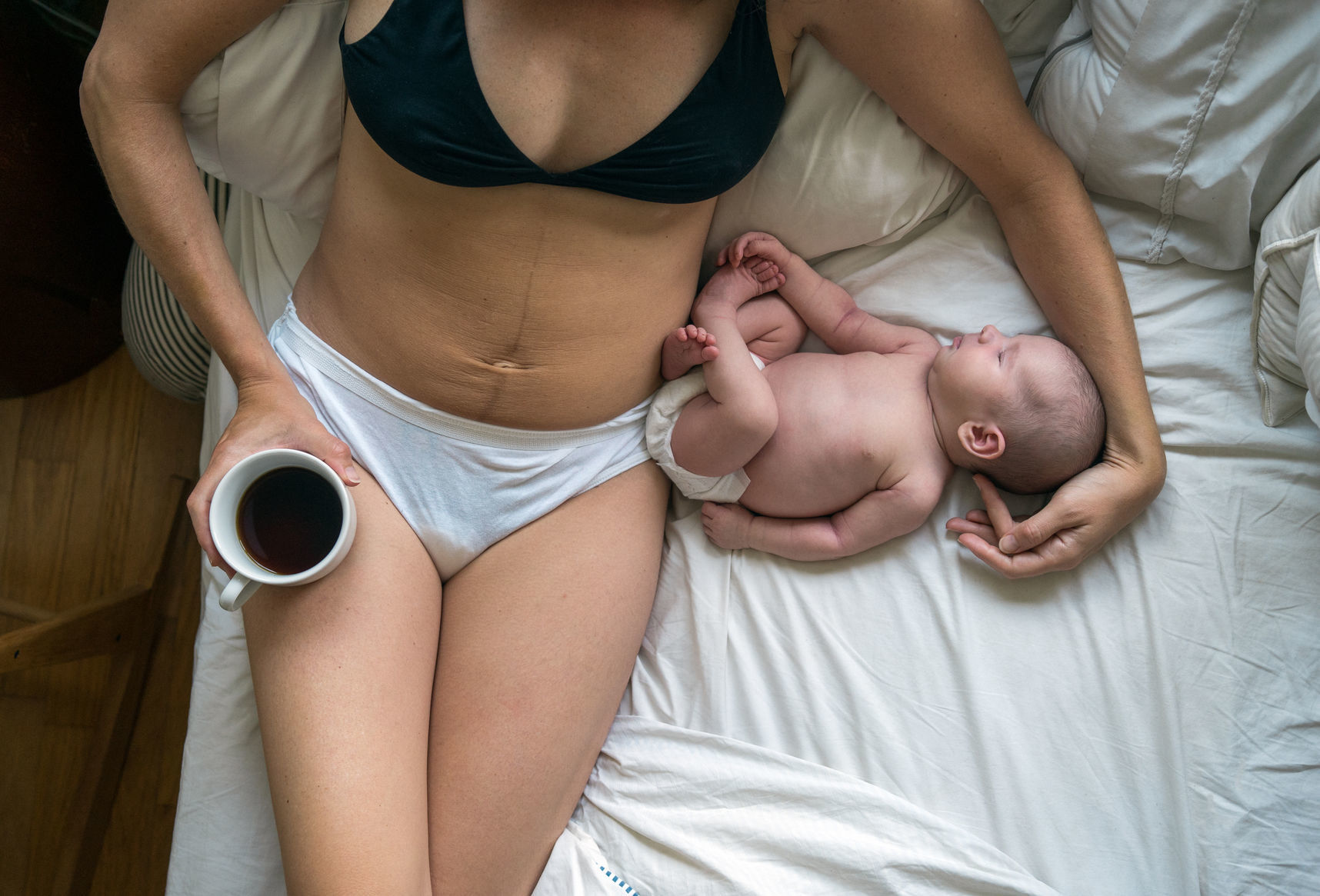 new parent and their baby, in bed, cuddling