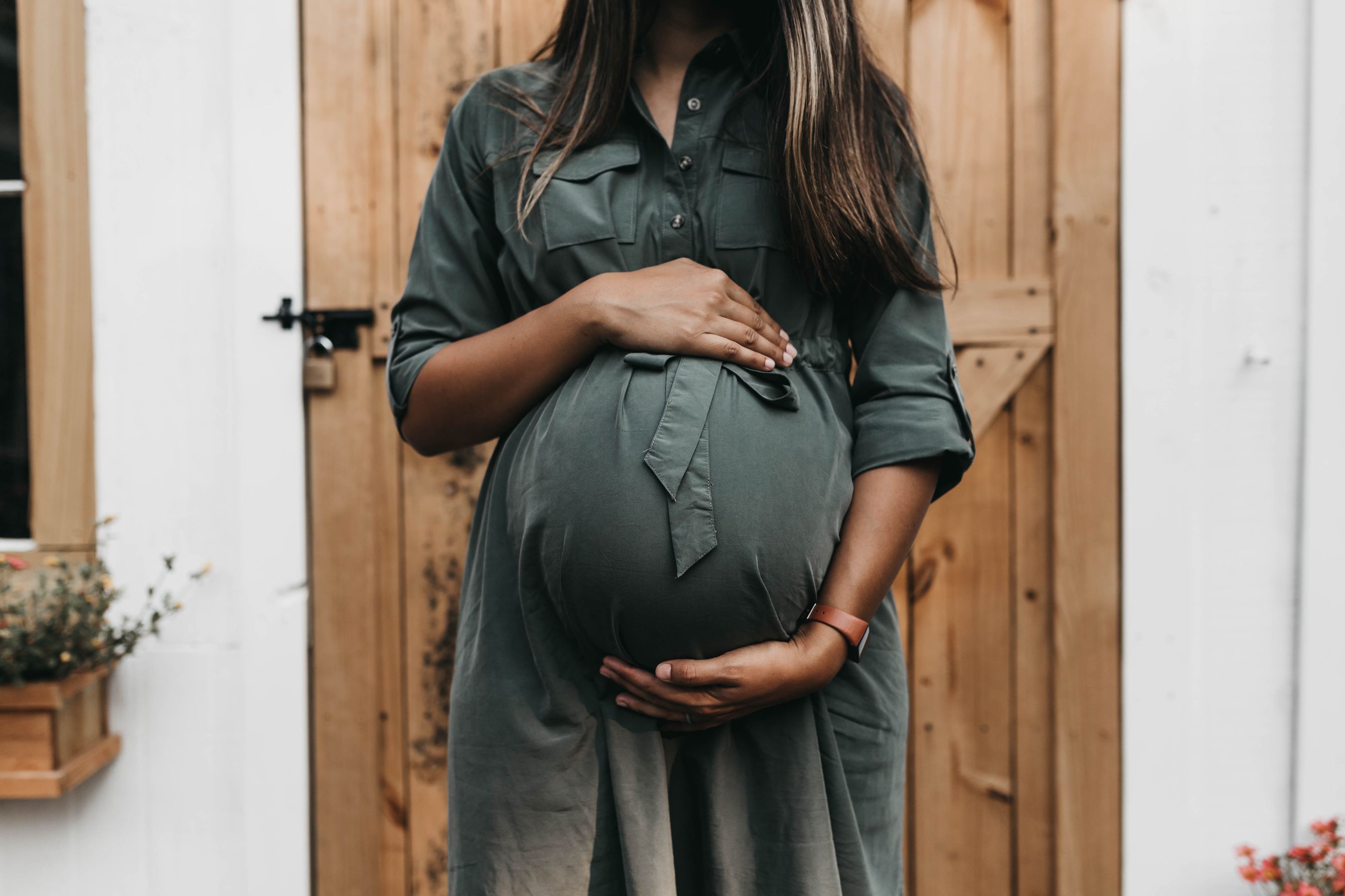 Pregnant woman standing against a door