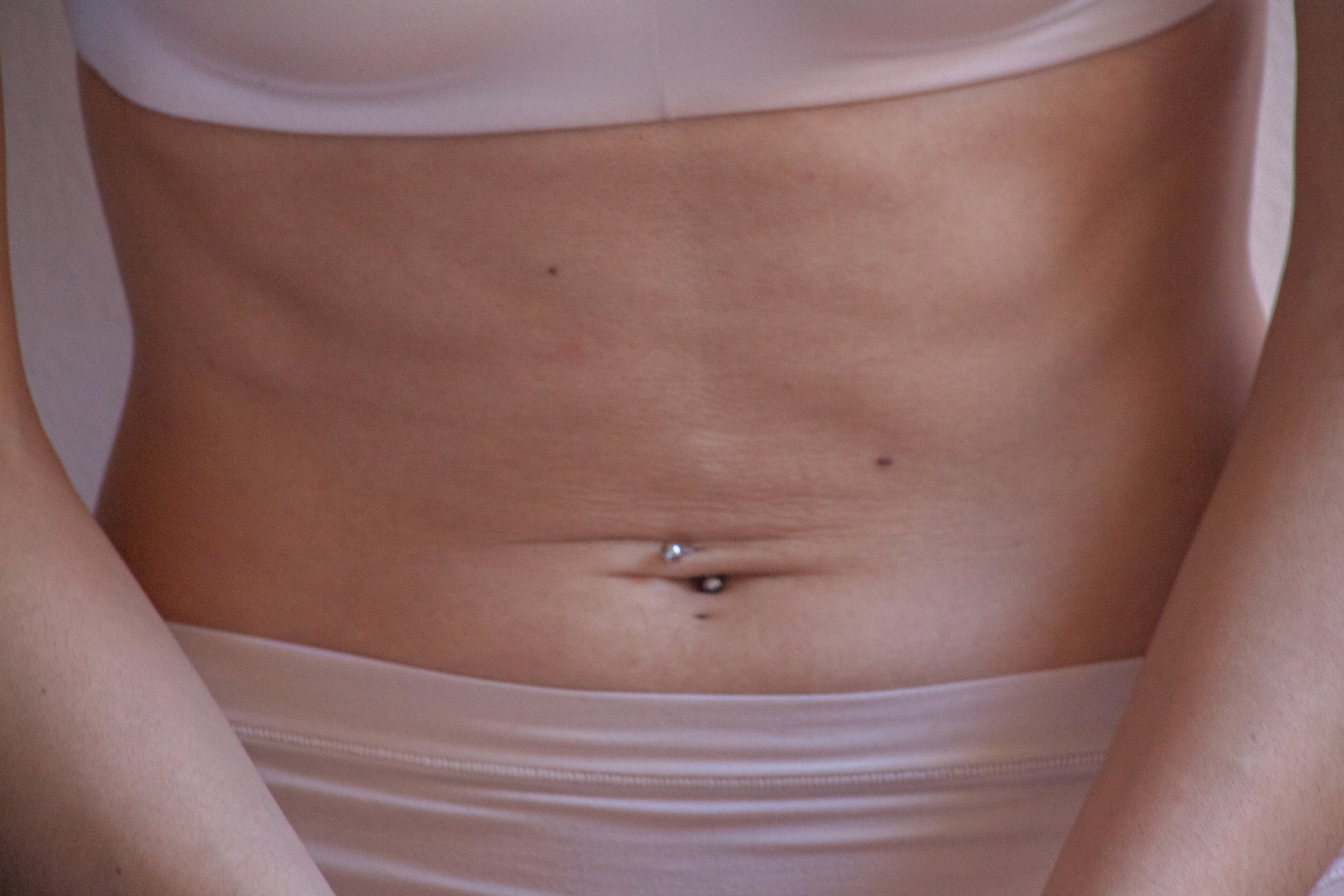 A bare tummy exposed, the person wearing flesh toned underwear