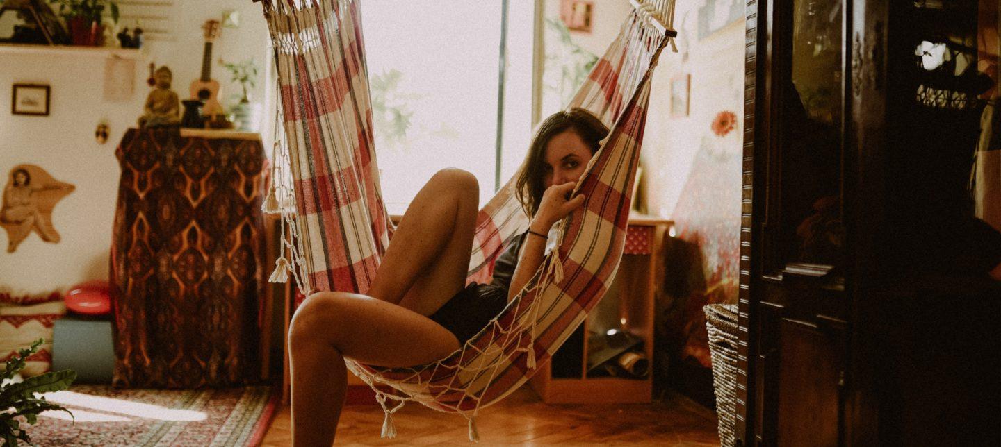 Woman sitting in hammock inside