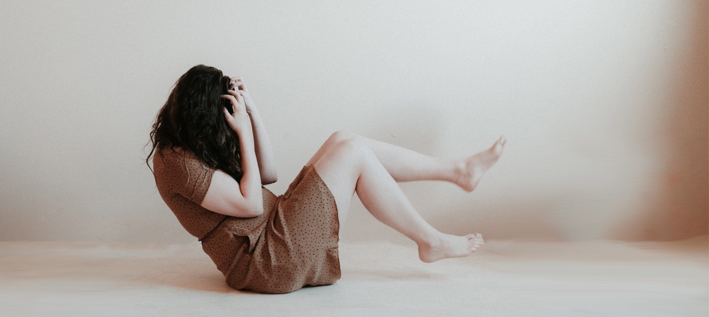 Woman on Floor holding her Head in Hands