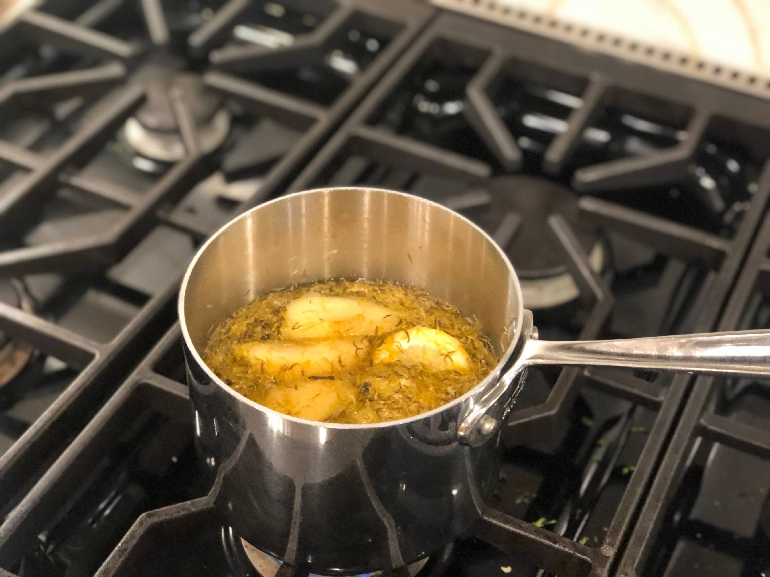 dandelions cooking on the stove in a metal pot