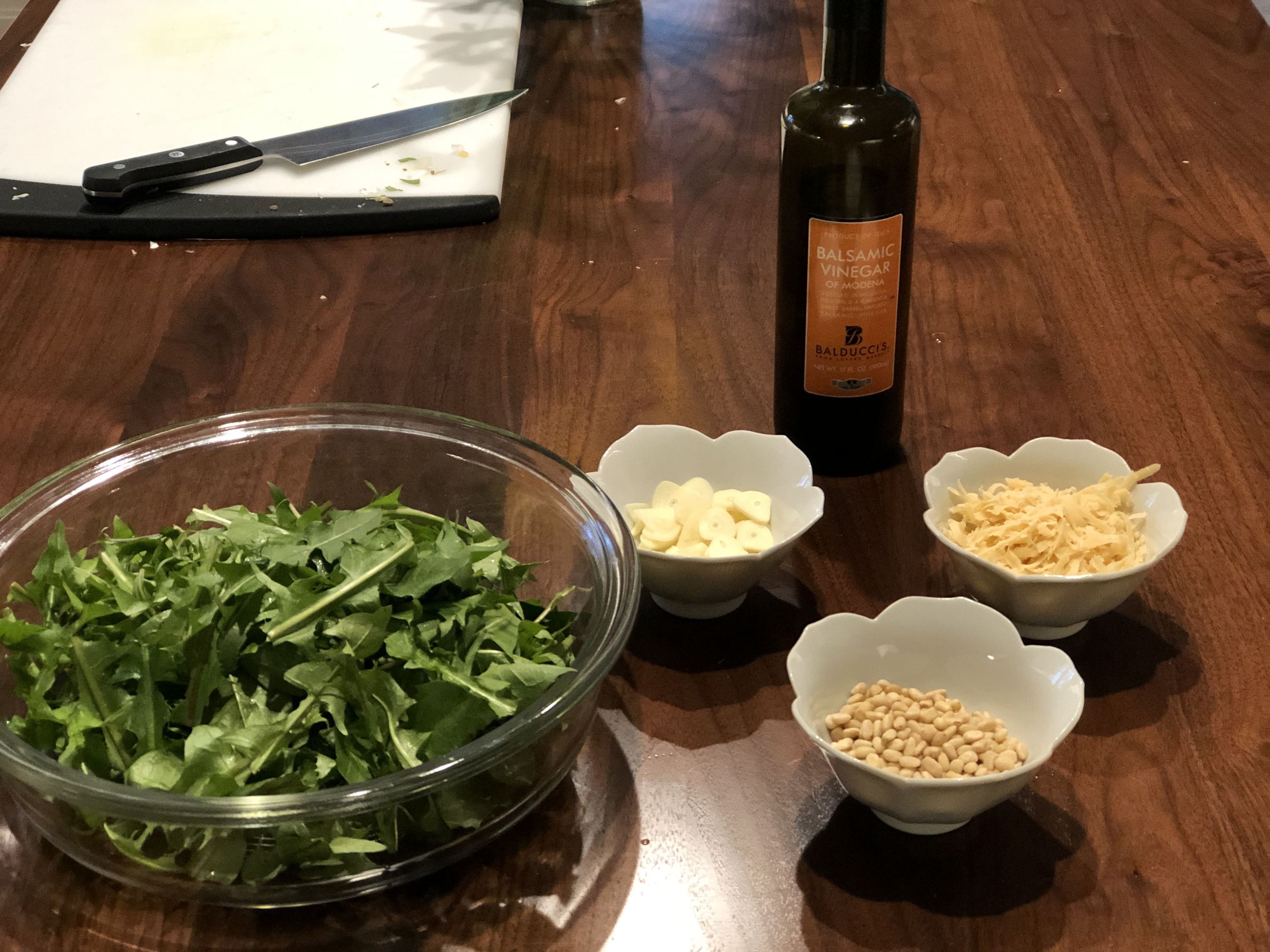 arugula, garlic, pine nuts, and olive oil on a table