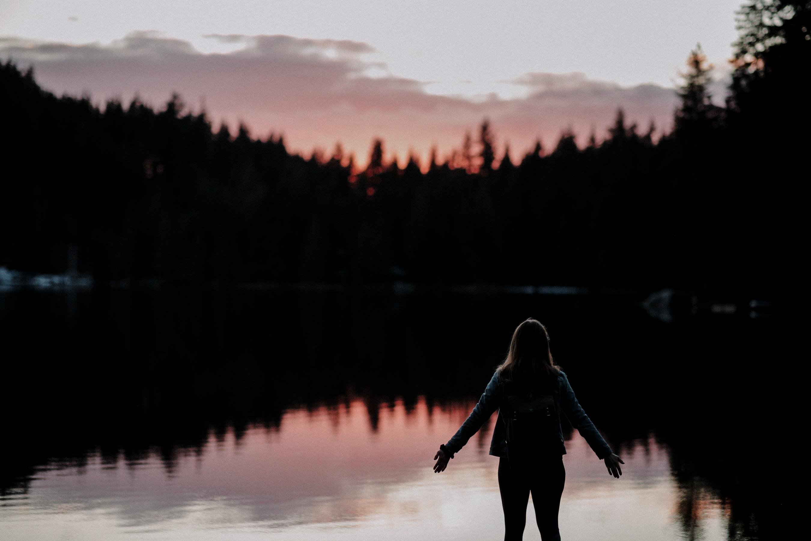 woman looking at sunset over lake 