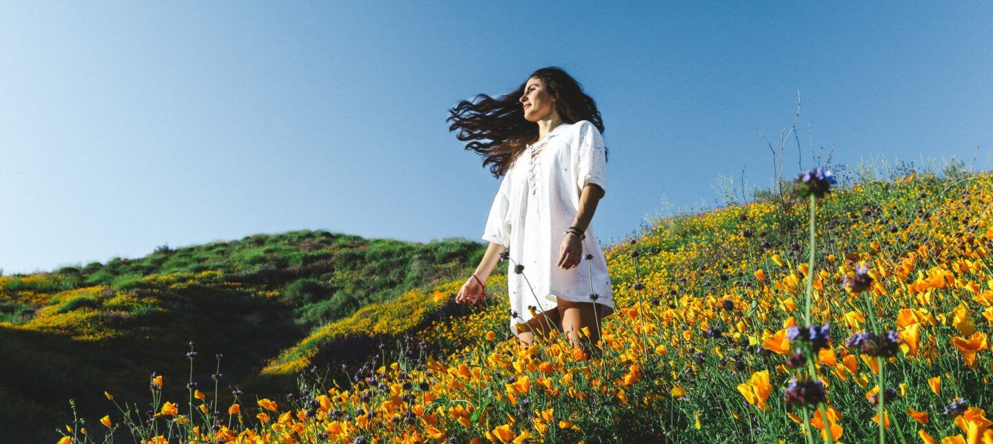 woman standing in sunlight field of flowers