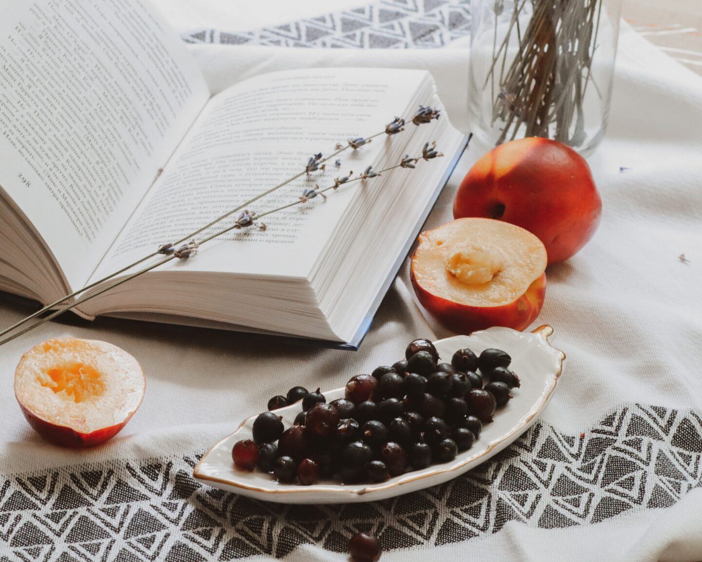 A book open on a table with peaches and grapes