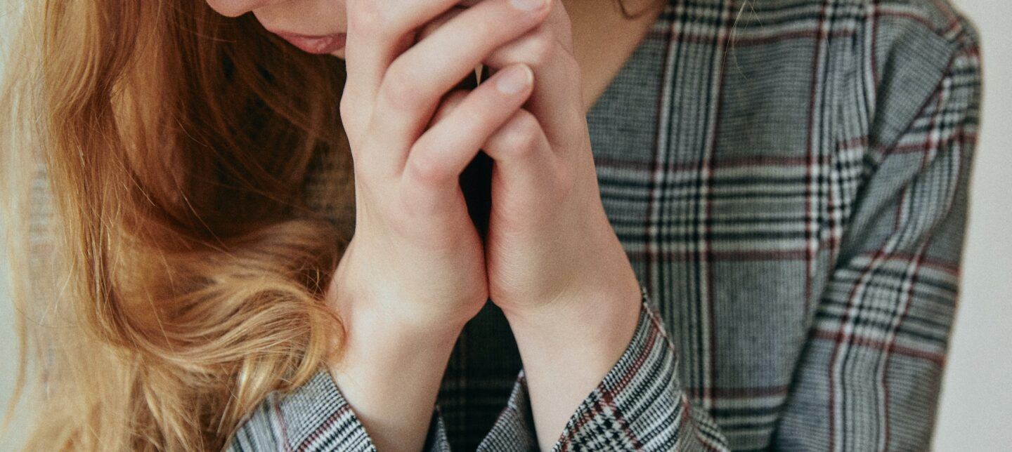 woman looking down with clasped hands