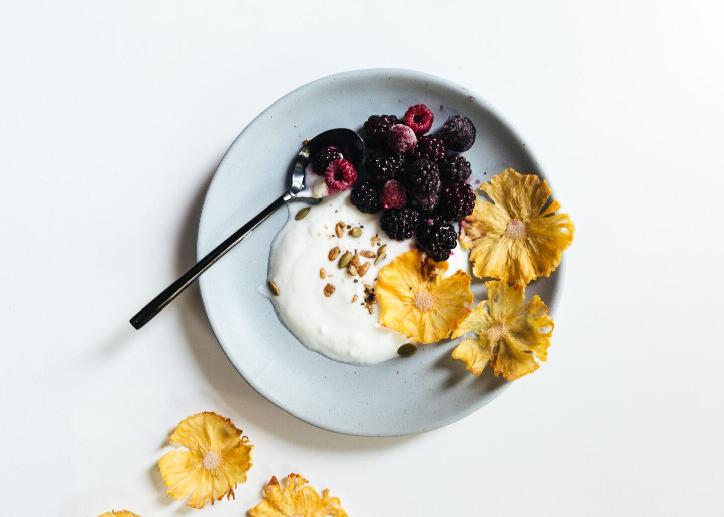Yogurt with dried pineapple flowers, frozen berries and keto granola