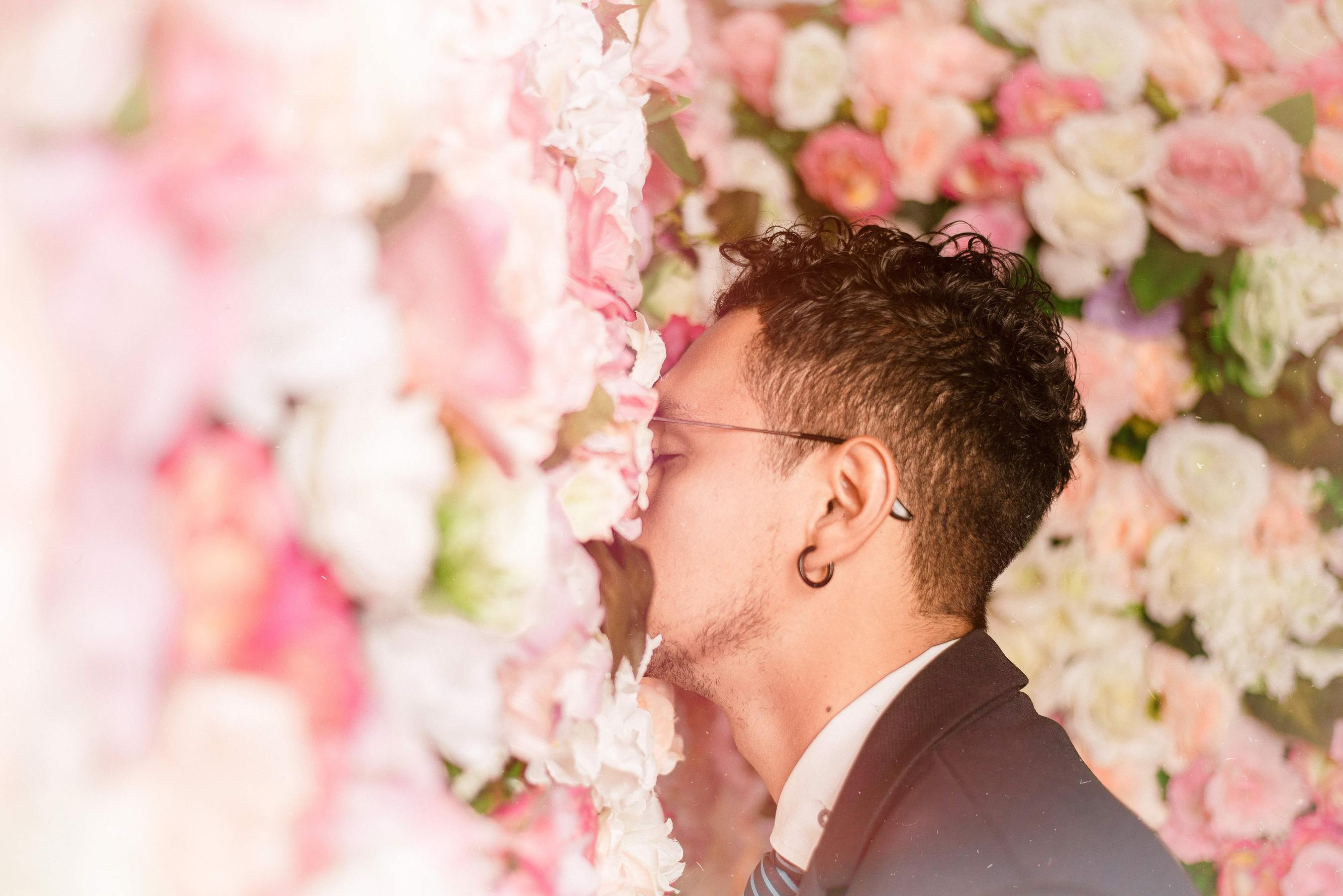 a man with his face in a wall of light pink roses