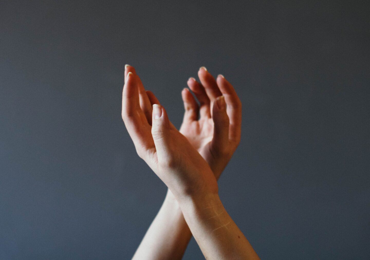hands in the air that are crossed against a grey background