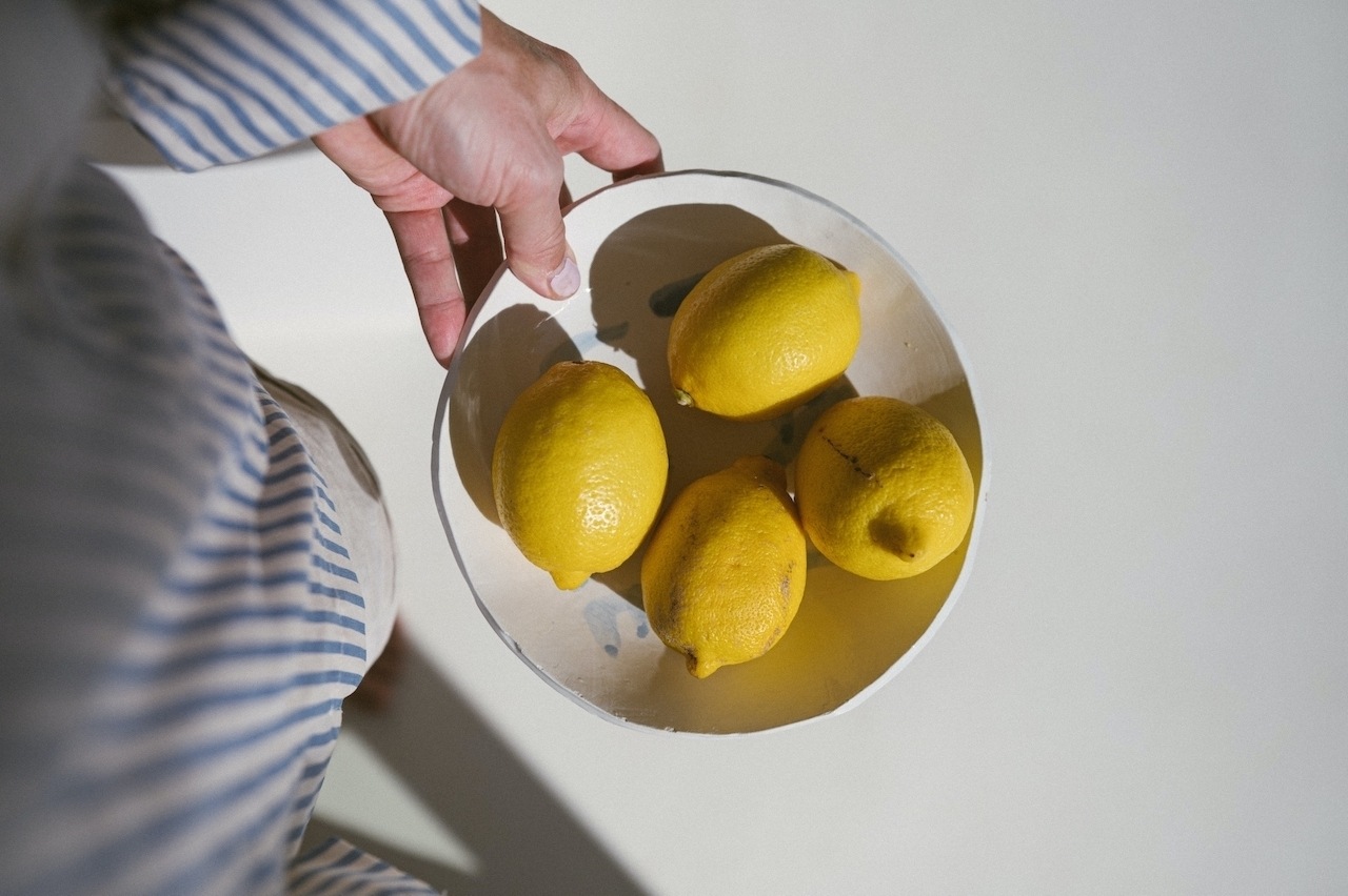 Woman with blue and white striped shirt holds a plate of lemons